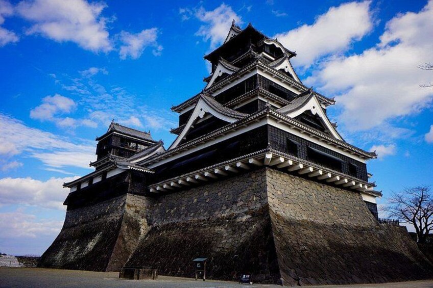A traditional Japanese castle with multiple tiers and a large stone base. 2