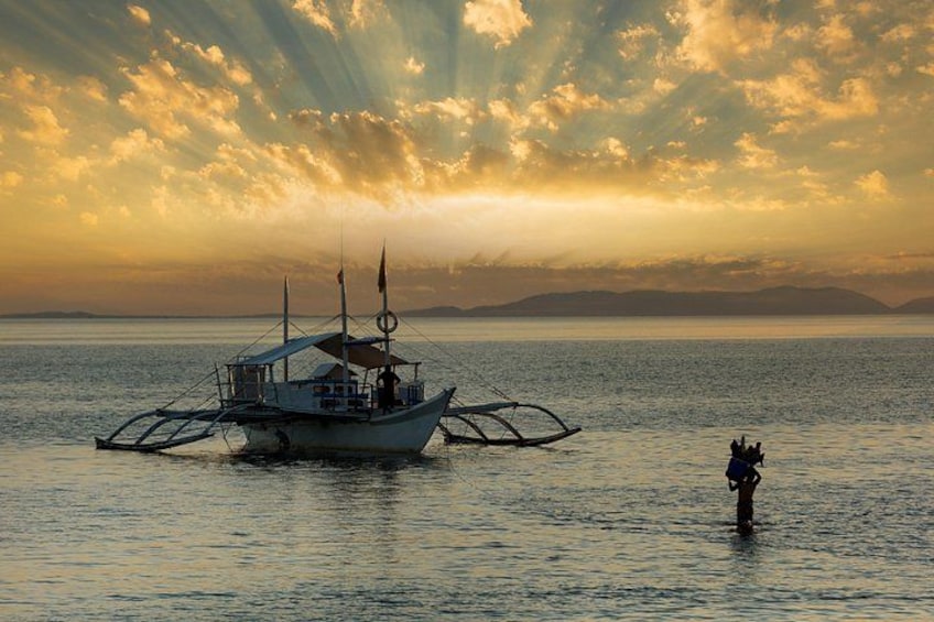 A traditional boat on calm waters with a person standing on the shore. 2