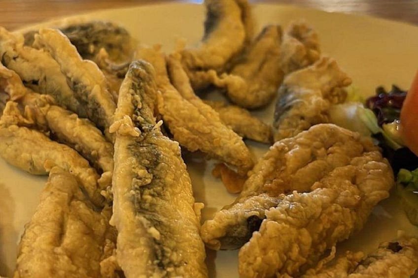 A plate of fried fish with a side of salad. 2