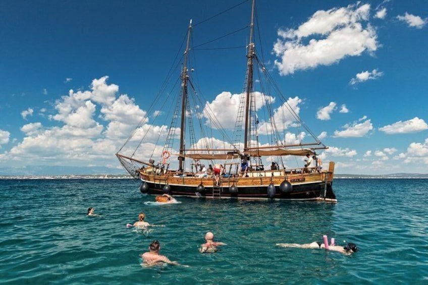 A sailing ship with people swimming and floating around it on the water. 4