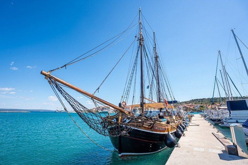 Un puerto con varios barcos pesqueros amarrados, un cielo azul despejado y mar en calma. 5