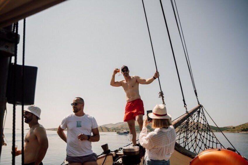 A group of people on a boat with a person standing on the edge of the deck. 3