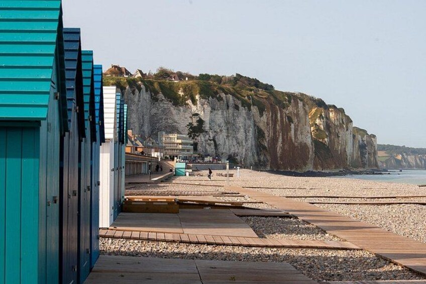 A beach with wooden walkways, a cliff, and buildings in the background. 3