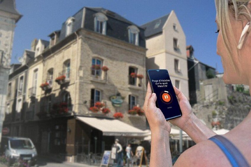 A person holding a smartphone with a map application, a building with flower boxes, and a clear blue sky. 4