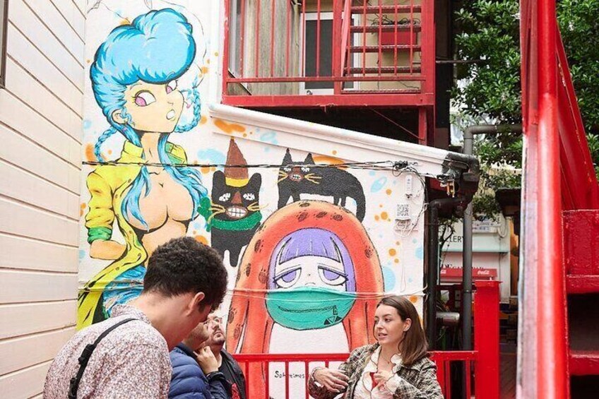 A mural on a building with a woman in a yellow jacket and a character with a purple face. 4