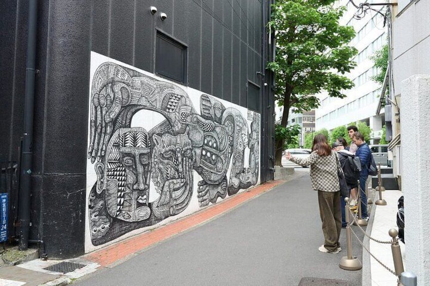 A mural on a building, a sidewalk, and a few people walking. 2