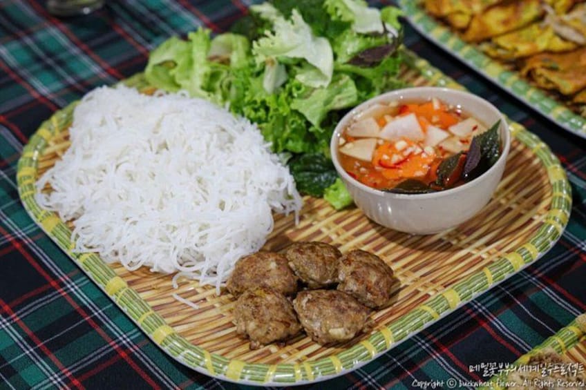 A plate with white noodles, lettuce, a bowl of soup, and grilled meat. 3