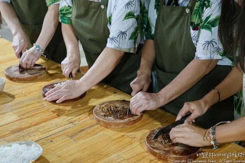 People preparing food, wearing aprons, and using wooden boards. 2