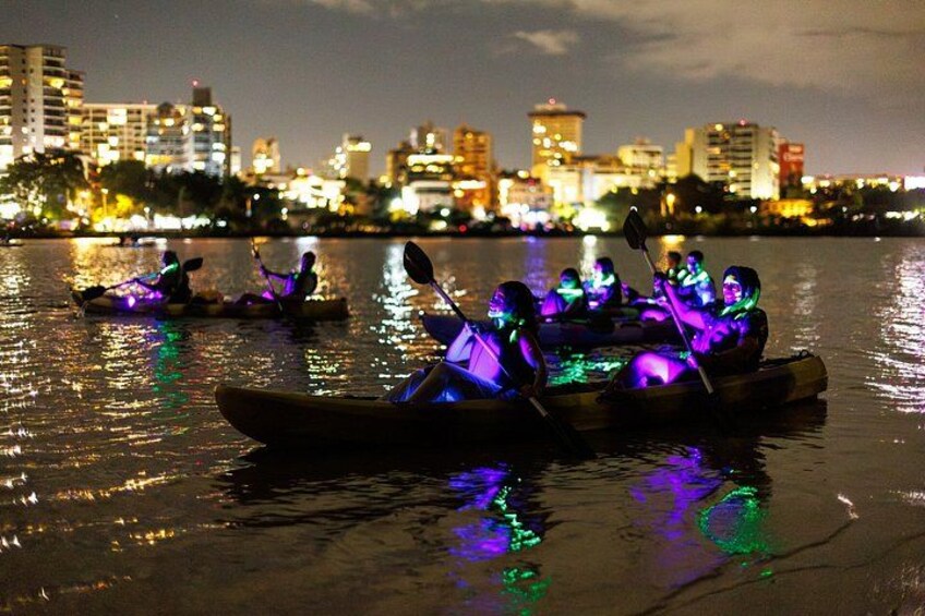 Deux bateaux illuminés sur une étendue d’eau, avec une vue sur les gratte-ciel d’une ville en arrière-plan. 3