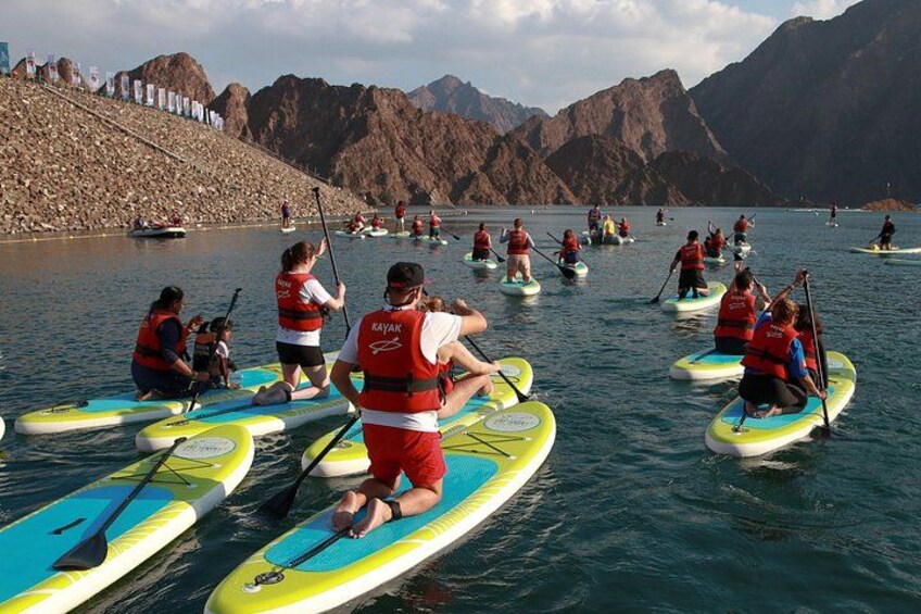 People on paddleboards in a lake with mountains in the background. 1