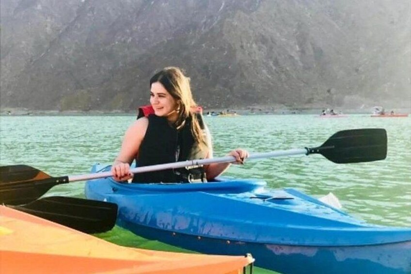 A person kayaking on calm water with mountains in the background. 4
