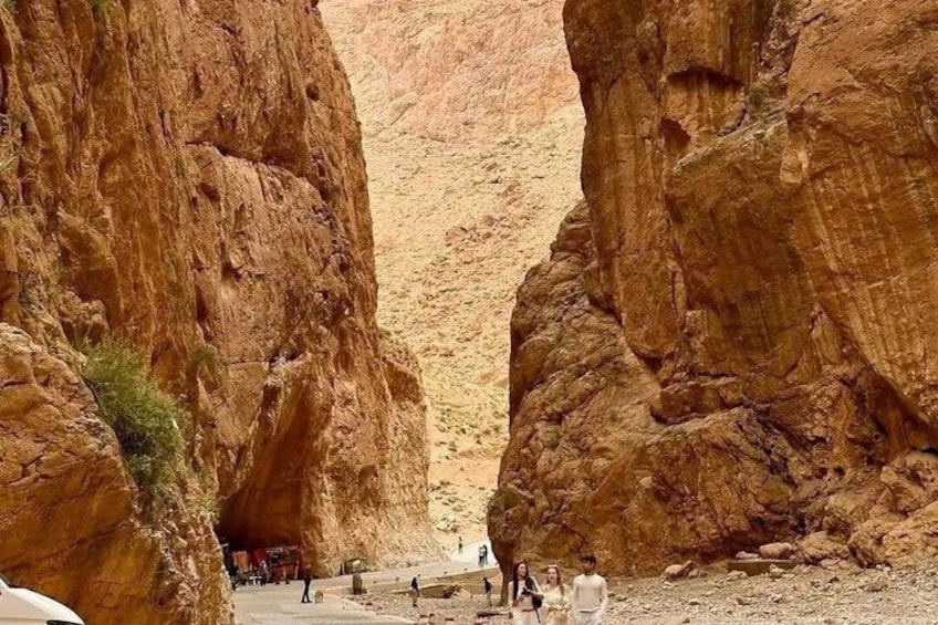 A canyon with red rock formations and a group of people standing at the bottom. 2