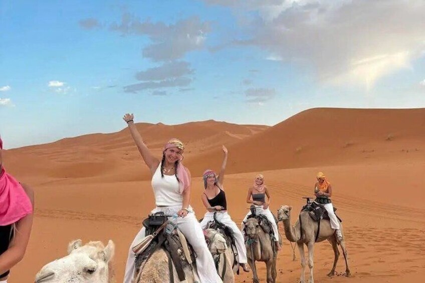 A group of people riding camels in a desert landscape. 1