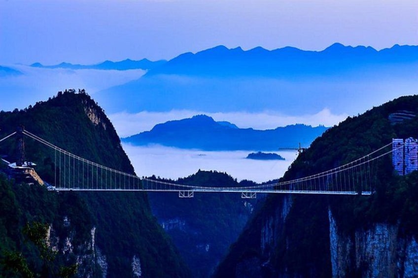 Un puente colgante que cruza un valle profundo, con acantilados escarpados a ambos lados. 4