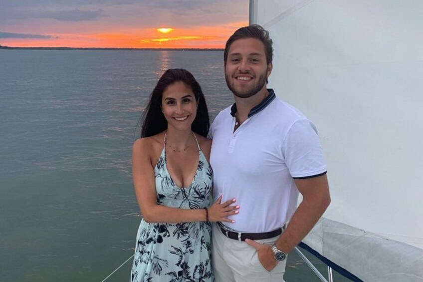 Deux personnes sur un bateau, avec un coucher de soleil en arrière-plan. 2