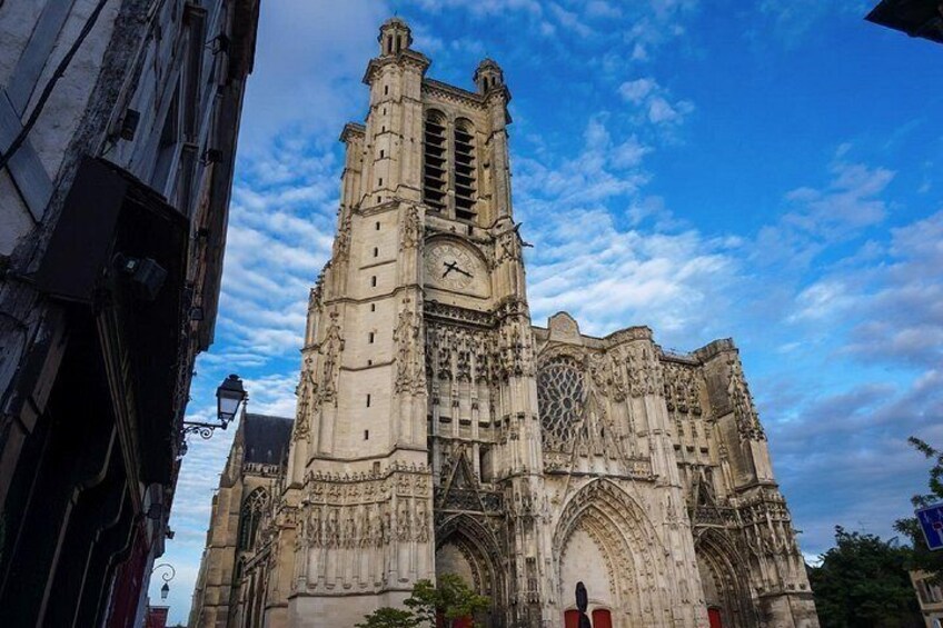 A historic cathedral with intricate architecture, a prominent clock tower, and a clear blue sky. 2