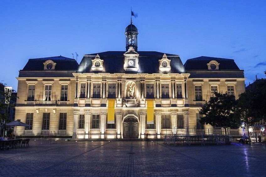 A large, historic building with a clock tower, ornate facade, and a central entrance. 3
