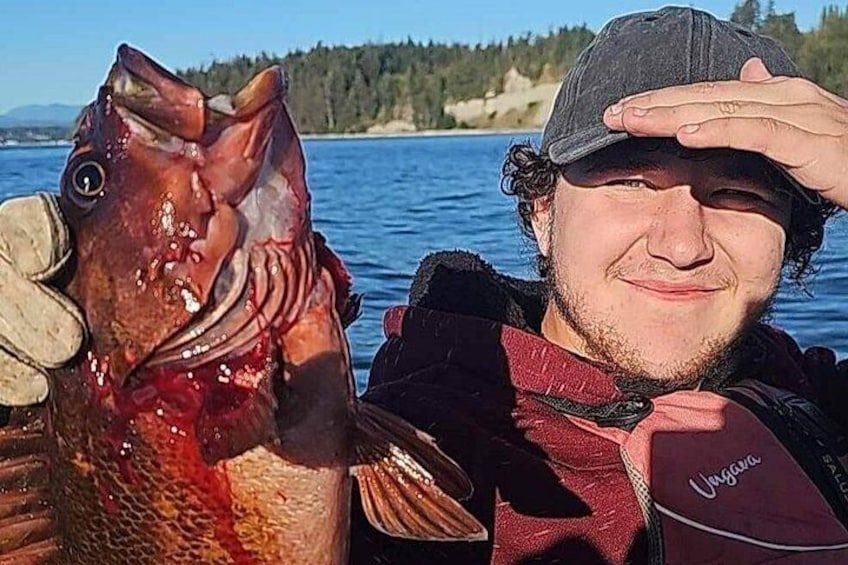 Une personne tenant un poisson près d ’une étendue d’eau, avec des arbres en arrière-plan. 3