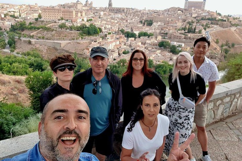 A group of people standing on a stone bridge with a cityscape in the background. 1