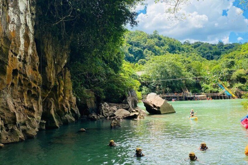 A river with clear water, rocky cliffs, and a person kayaking. 3