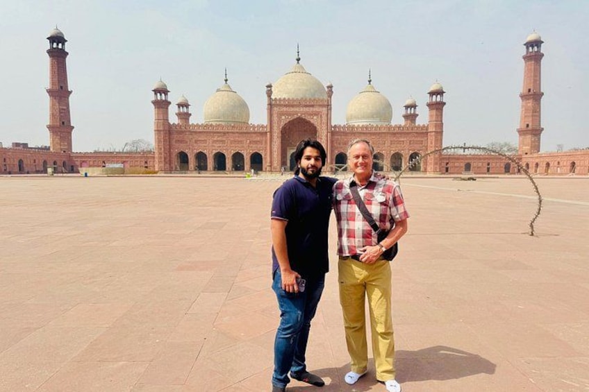 Two people standing in front of a large, historic building with domes and minarets. 3