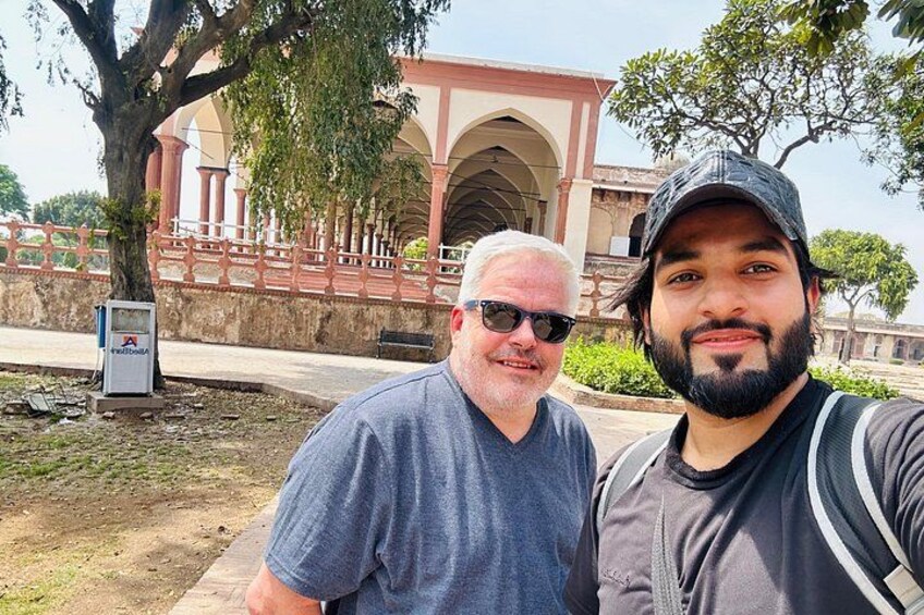 Two people standing in front of a building with arches and a tree. 5