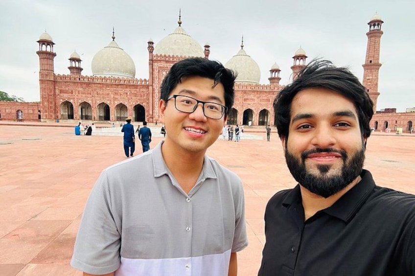 Two men in front of a large historical building with domes and minarets. 1