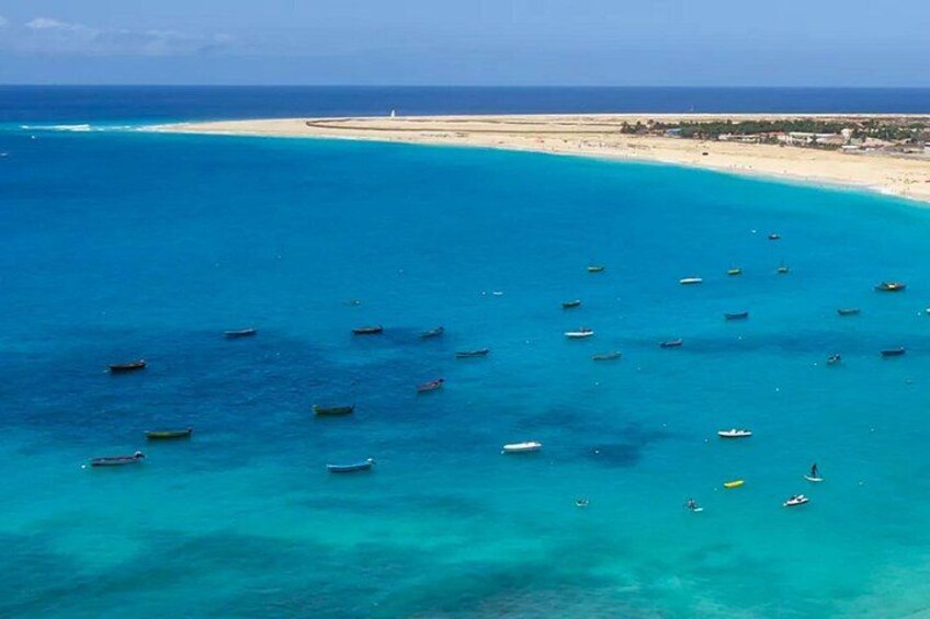 A coastal area with turquoise waters, boats, and a sandy beach. 2