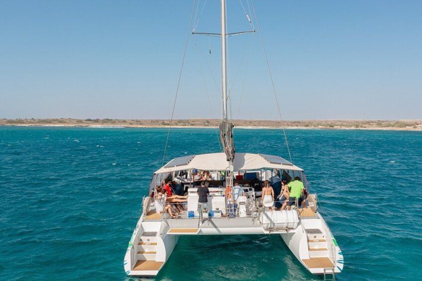 A catamaran sailing on turquoise waters with passengers enjoying the view. 3