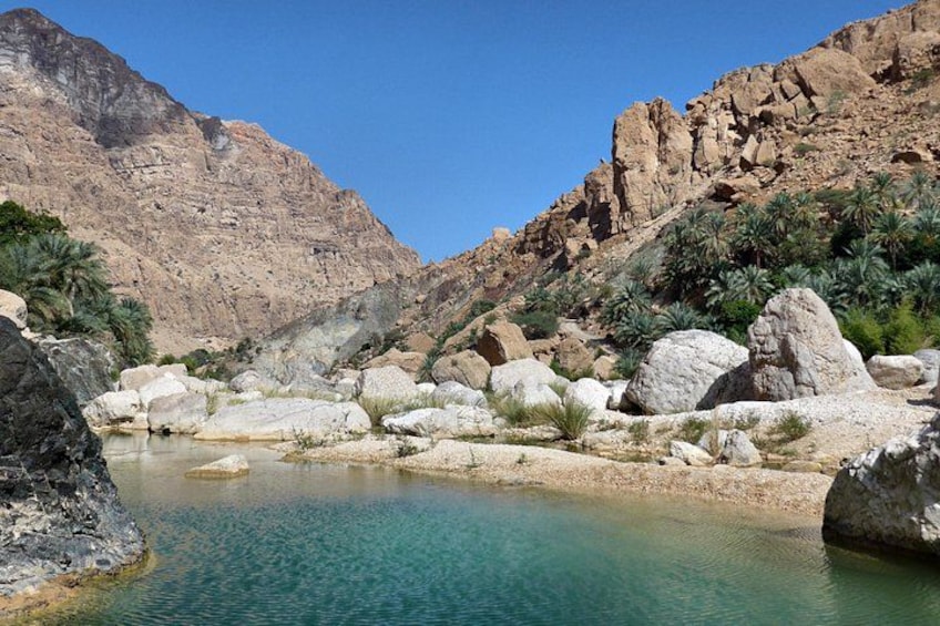 Une piscine d’un bleu turquoise éclatant, entourée de gros rochers et d’une végétation clairsemée, dans une région montagneuse. 5