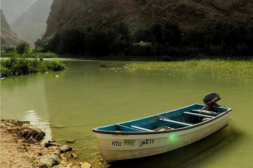 Une petite embarcation à moteur navigue sur une rivière paisible, bordée de verdure et de falaises rocheuses. 3