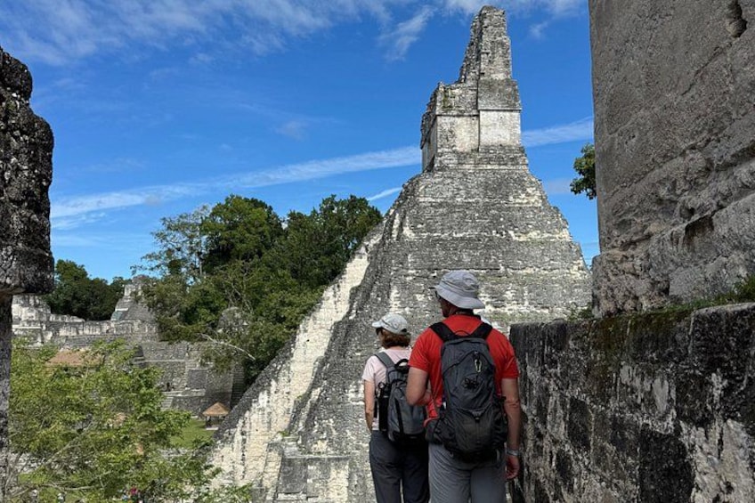 A large ancient pyramid structure with tourists observing it. 1