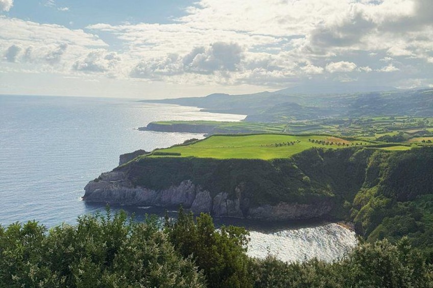 A coastal landscape with cliffs, a grassy field, and a body of water. 2
