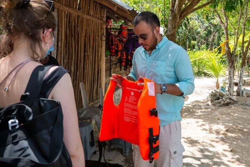 A person holding a bright orange bag, another person with a backpack, and a wooden structure in the background. 4