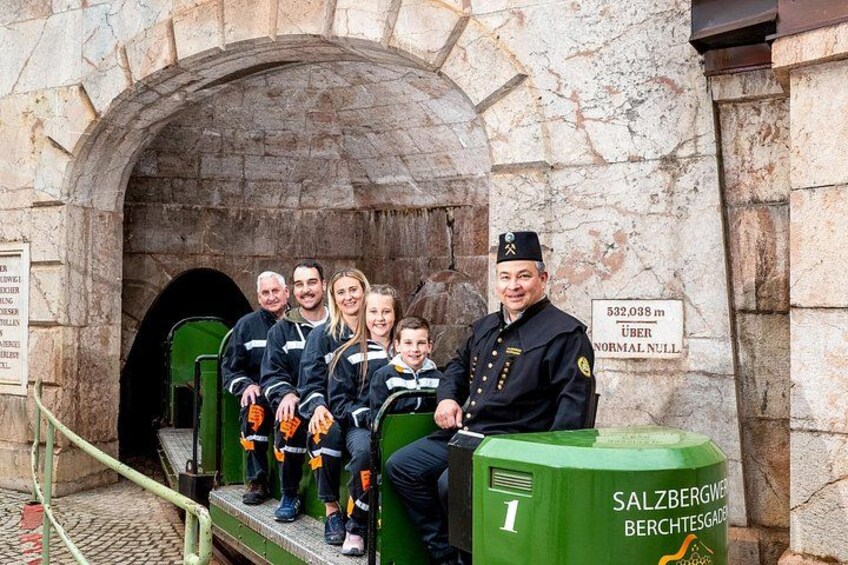 A family and a man in uniform sitting on a green platform with a sign indicating a height of 532,038 meters above normal null. 2