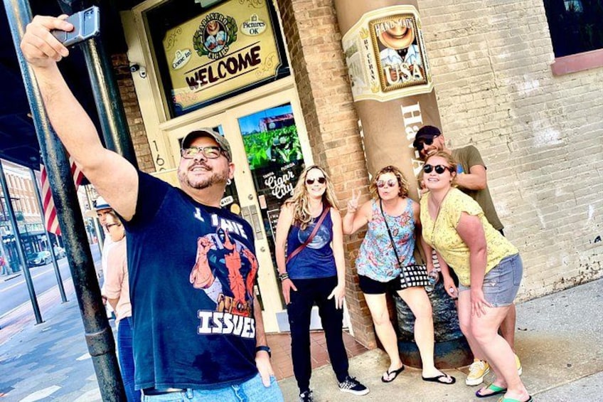 Un groupe de personnes posant devant un bâtiment sur lequel on peut voir une pancarte « Bienvenue » et le logo « Handy Dandy USA ». 3