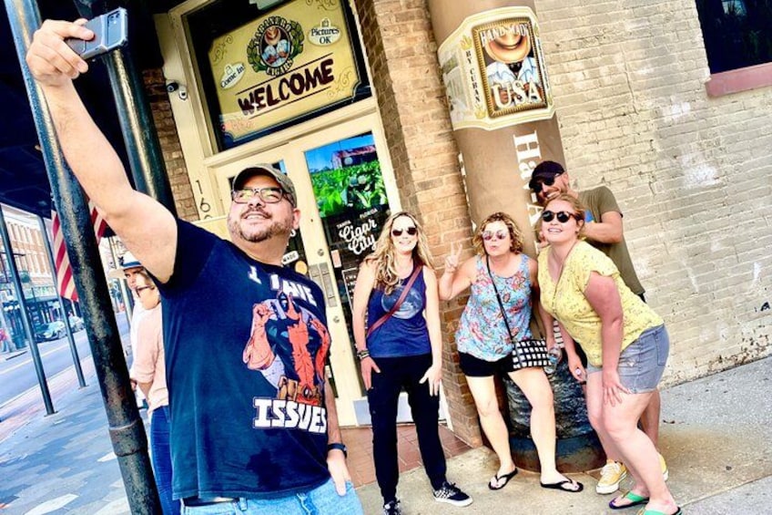 A group of people posing in front of a building with a 'Welcome' sign and a 'USA' sign. 2