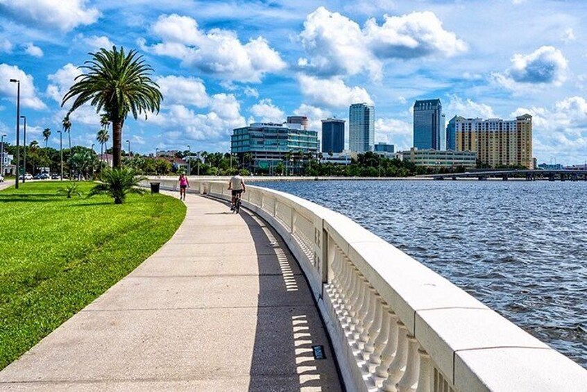A waterfront walkway with a city skyline in the background. 4