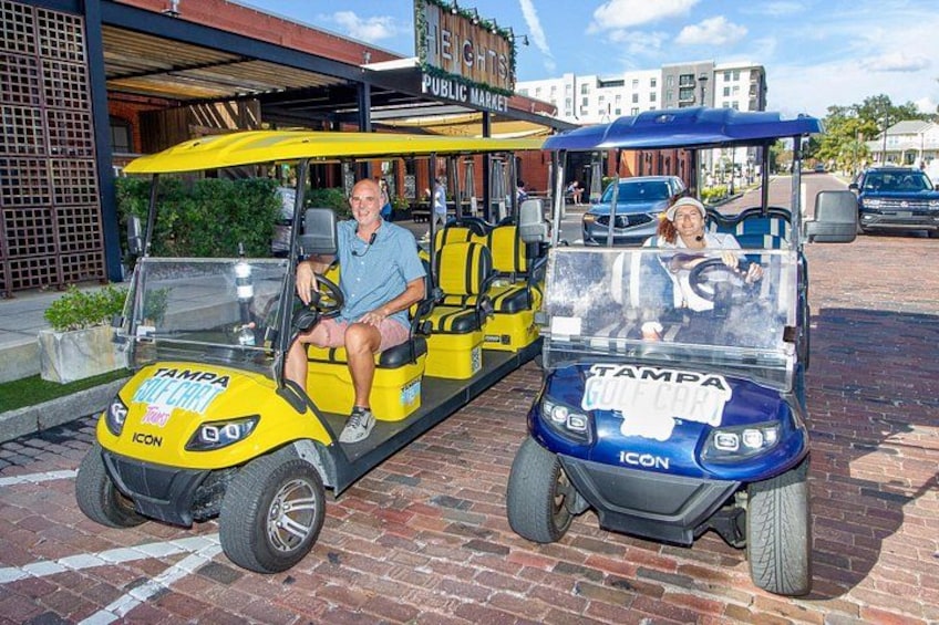 Two golf carts with 'Tampa Golf Cart' written on them, parked on a brick pavement. 3