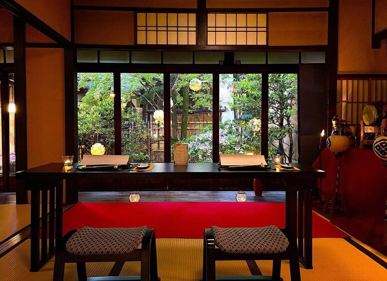 A traditional Japanese room with tatami flooring, a low table, and a view of a garden through shoji screens. 1
