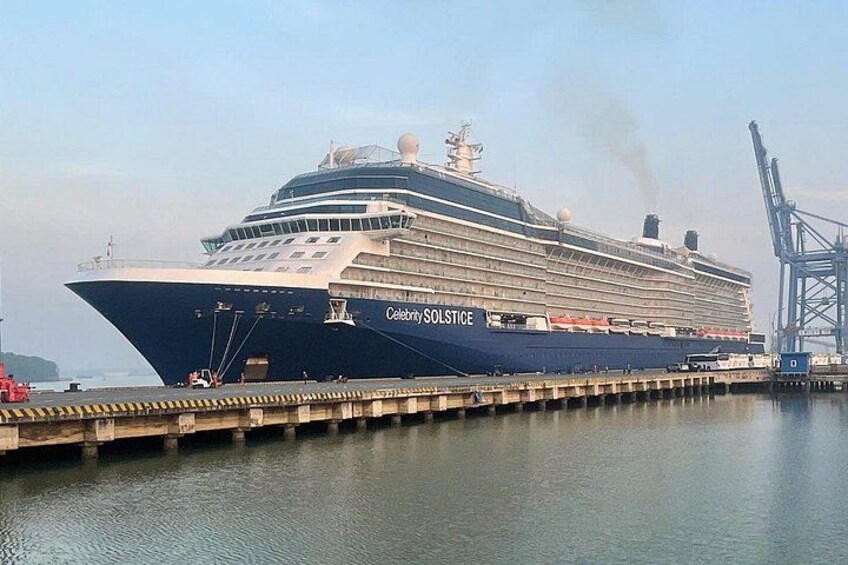 A large cruise ship named Celebrity Solstice docked at a port with cranes and a calm water body in the background. 1