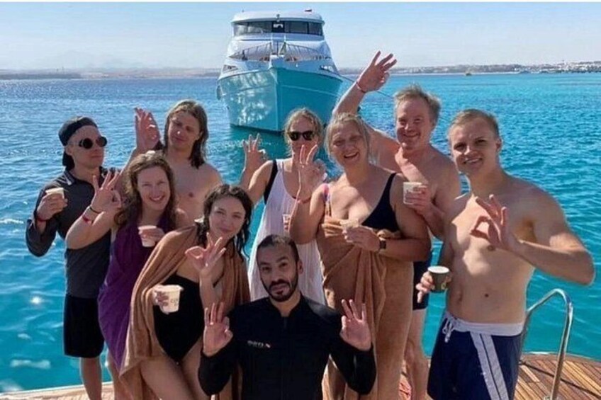 Un grupo de personas en un barco con un gran carguero al fondo. 4