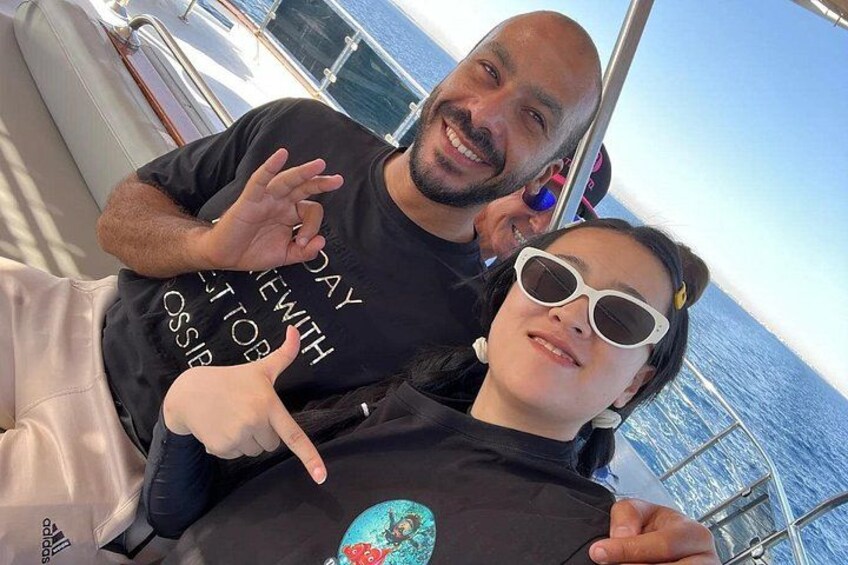 Una persona con camiseta negra y diseño gráfico, sentada en un bote con vista al océano. 3