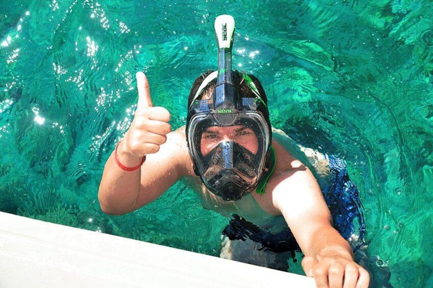 A person underwater in clear water, wearing a snorkel mask and giving a thumbs-up. 3