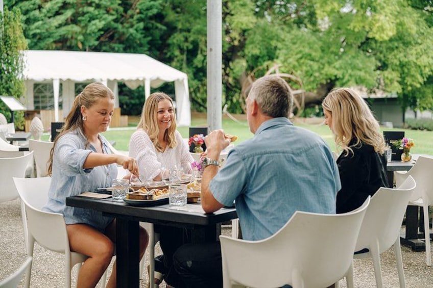 A group of people dining outdoors at a table with food and drinks. 4