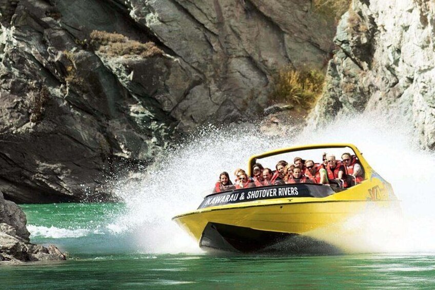 A yellow boat with passengers, labeled 'MARAU & SHOTOVER RIVERS,' navigating through water with a rocky backdrop. 1