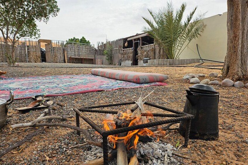 An outdoor area with a fire pit, a colorful mat, and a stone wall. 5