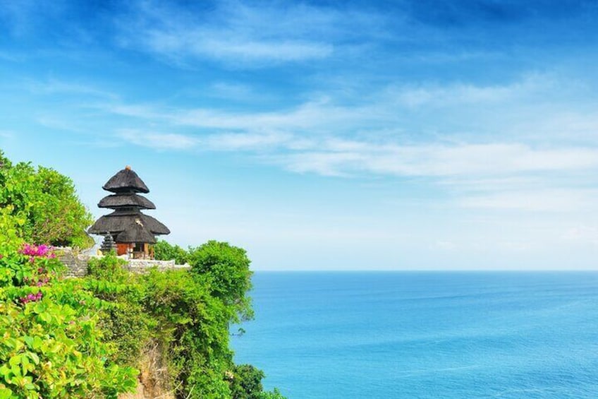 A traditional multi-tiered pagoda on a lush cliff overlooking the ocean. 2