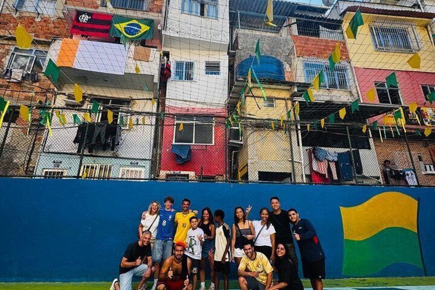 A group of people posing in front of a wall with a large Brazilian flag. 2