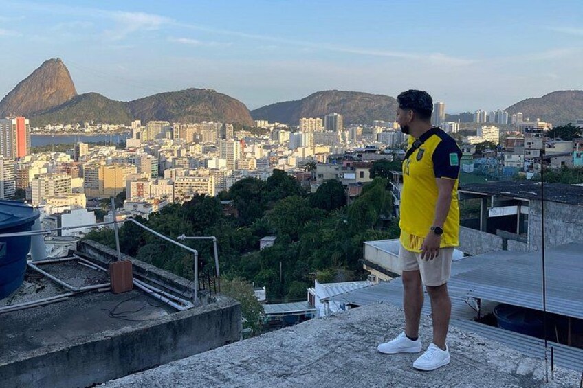 Eine Person steht auf einem Dach und blickt auf eine Stadtlandschaft mit Bergen im Hintergrund. 3